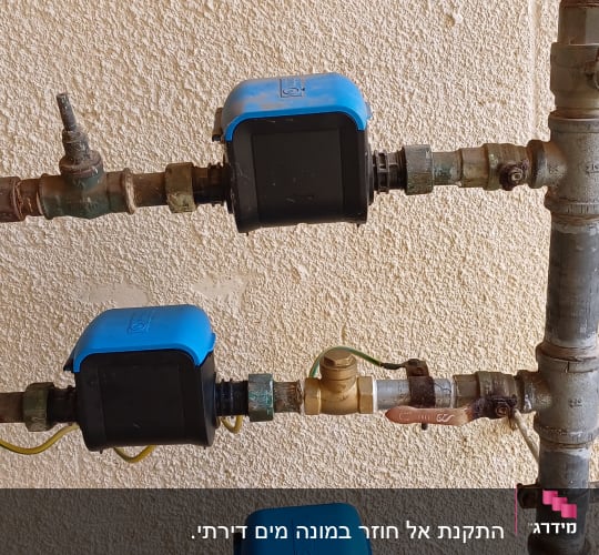 צינורות עם ברזים ומדי מים כחולים על קיר